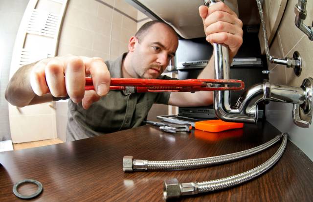 handyman fixing a sink inside the house